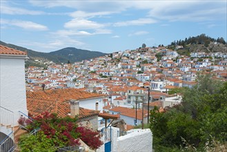 View of a picturesque village with white houses and red roofs under a cloudy sky, Poros, Poros