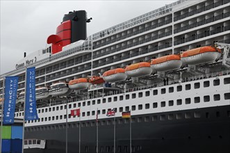 The Queen Mary 2 in the harbour with lifeboats and advertising banners, Hamburg, Hanseatic City of