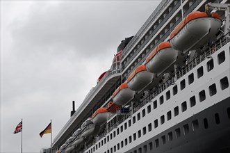 Side view of a cruise ship Queen Mary 2, with lined up lifeboats and flags, Hamburg, Hanseatic City