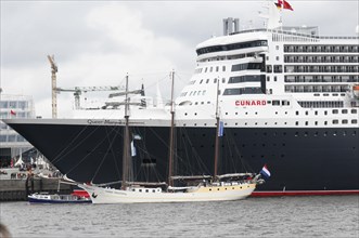 A small sailing boat next to the giant cruise ship Queen Mary 2, Hamburg, Hanseatic City of