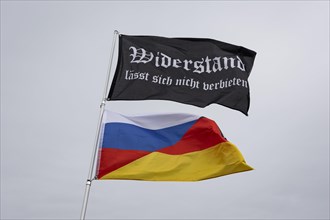 A waving flag with the inscription 'AeoeWiderstand laesst sich nicht verbieten'Aeo and a
