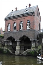 Fleetsschloesschen, historic brick building in Gothic style on a waterway with plants, Hamburg,