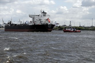 A tanker and a tugboat in the turbulent waters of a harbour, Hamburg, Hanseatic City of Hamburg,