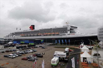 Large cruise ship Queen Mary 2, at a harbour with parked vehicles and people, Hamburg, Hanseatic