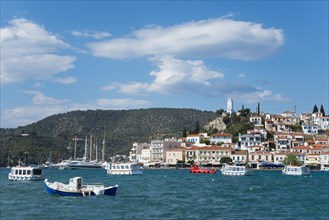 View of a picturesque coastal town with colourful boats on clear blue water under a partly cloudy