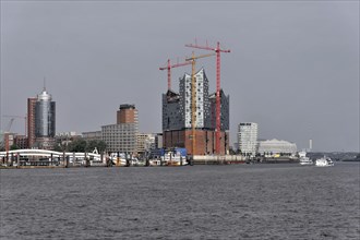 View of the Elbe Philharmonic Hall in Hamburg with construction cranes in cloudy weather, Hamburg,