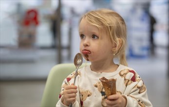 Interior shot, girl, 2-3 years, blonde, eating chocolate ice cream, ice cream, waffle, spoon, mouth