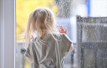 Little girl, 2-3 years, blonde, portrait, in front of window, looking at rain, raindrops on window