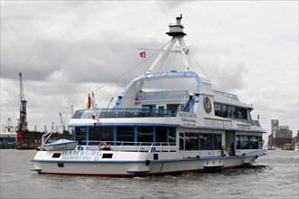 An excursion boat with a blue hull and white superstructure sails through Hamburg harbour, Hamburg,