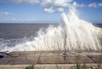 Waves hit sea wall illustrating hydraulic action and corrasion coastal erosion, East Lane, Bawdsey,