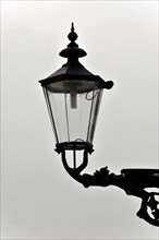 Silhouette of a street lamp in front of a bright, overcast sky in black and white, Hamburg,