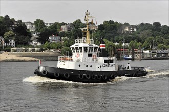 A tugboat sailing on a river (Elbe) with a city in the background, Hamburg, Hanseatic City of