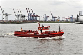 A red fire boat sailing through the water in Hamburg harbour, Hamburg, Hanseatic City of Hamburg,