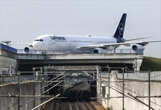 A Lufthansa Airbus A340-300 with the name of the city of Dorsten crosses a railway bridge at