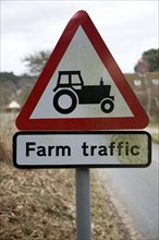 Red triangular road sign for farm traffic, UK