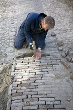 Man repairing cobbled street, Zuiderzee museum, Enkhuizen, Netherlands