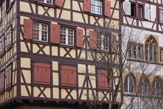 Pastel orange facade of a half-timbered house with windows and red shutters in the historic centre