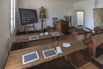 Chalkboards and blotting cloths on the school desks, blackboard and teacher's desk in a 19th