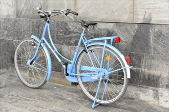 Blue bicycle leaning against a grey wall on a cobbled street, Hamburg, Hanseatic City of Hamburg,