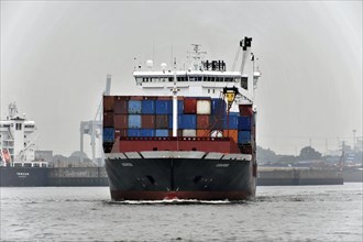 A large container ship loaded with colourful containers sails through the port, Hamburg, Hanseatic