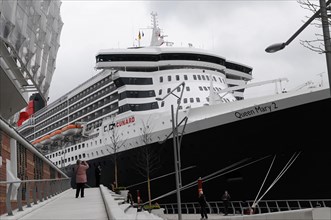 A large cruise ship Queen Mary 2, at the dock, people walking on the jetty, Hamburg, Hanseatic City