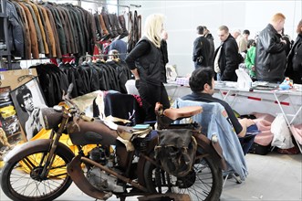 Flea market stand with vintage motorbike, clothes and people in the background, Stuttgart Messe,