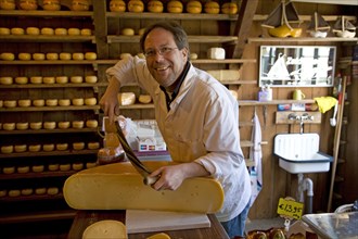 Shopkeeper cutting cheese in cheese shop and warehouse, Zuiderzee museum, Enkhuizen, Netherlands