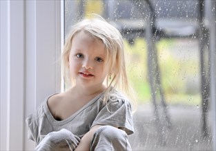Little girl, 2-3 years, blonde, portrait, in front of window, rain, raindrops on window pane,