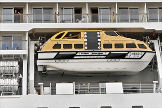 Detail, AIDALuna, A yellow lifeboat on the side of a cruise ship with people in it, Hamburg,