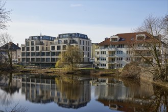 Residential and commercial buildings are reflected on the water surface of the swan pond in Minden,
