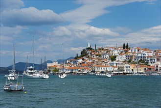 View of an idyllic coastal town with white houses and sailing boats on clear blue water, view from
