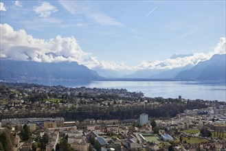 View of Vevey and Lake Geneva with cloudy, misty mountains in the background from Jongny,