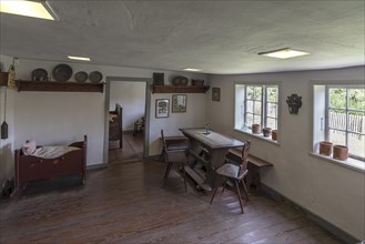 Dining room with cradle in a historic farmhouse from the 19th century, Open-Air Museum of Folklore