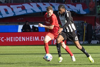 Football match, Nikola DOVEDAN 1.FC Heidenheim, left, in a duel for the ball with Jordan SIEBATCHEU