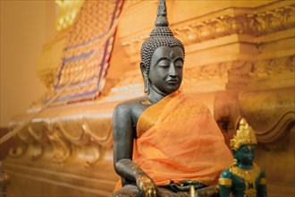 A serene Buddha statue draped in orange cloth inside a temple. Ayutthaya, Thailand, Asia
