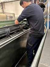 Vertical portrait of a man placing the blades for cutting sheet metal on a metal cutting machine.