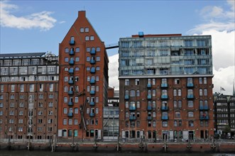 Architecturally diverse buildings on a riverbank (Elbe) with reflections in the water, Hamburg,