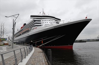The Queen Mary 2 moored at the quay with a dramatic sky in the background, Hamburg, Hanseatic City