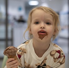 Indoor photo, girl, 2-3 years, blonde, eating chocolate ice cream, ice cream, waffle, mouth