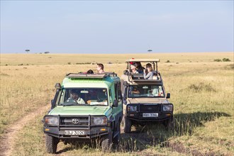 Tourists in safari cars watching wildlife on the savannah, Maasai Mara National Reserve, Kenya,