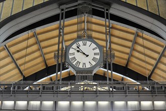Modern railway station clock on a vaulted ceiling with glass and metal structures, Hamburg,