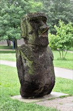 A moss-covered stone sculpture, similar to the Moai from Easter Island, in the park, Hamburg,