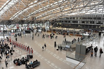 Spacious view of an airport terminal with travellers and a modern roof construction, Hamburg,