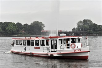 Passenger ship with red details sailing on a river under a grey sky, Hamburg, Hanseatic City of