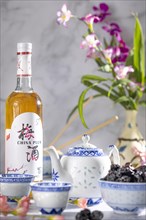 Asian tea set with blue patterns, a bottle of Chinese plum wine and dried fruit