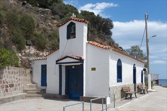 Small white chapel with blue accents located next to a quiet street, Holy Cross Church, Poros,