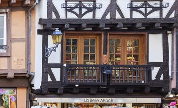 Balcony and window on a half-timbered house and the shop La Belle Alsace in the old town centre of