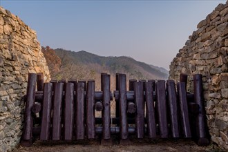 Closeup of wooden log blockade at gate of mountain fortress made of flat stones in Boeun, South
