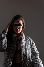 Studio portrait with grey background of a futuristic woman using mixing reality intelligent goggles