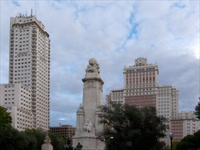 View of a monument in front of modern skyscrapers under a cloudy sky Madrid Spain